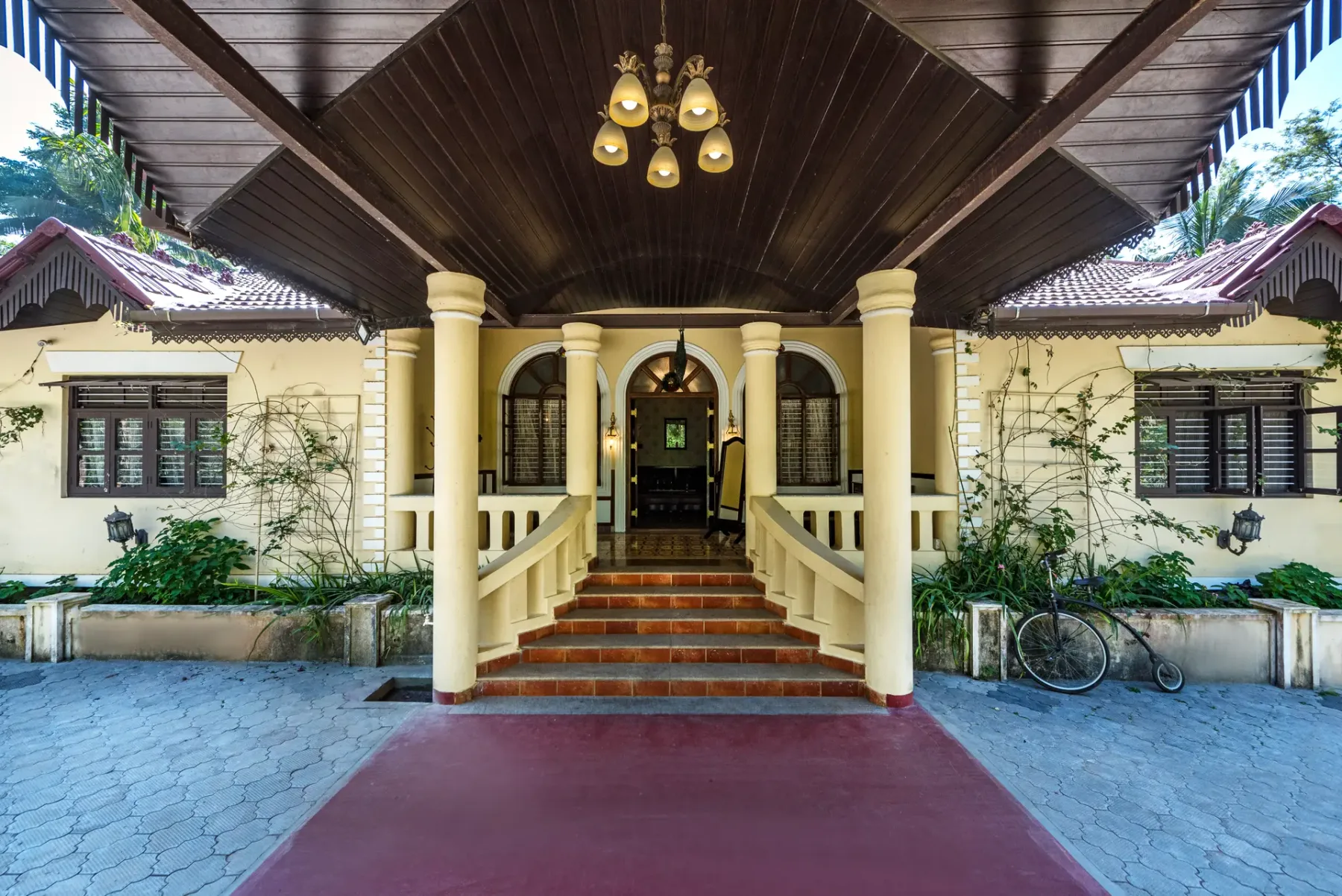 A covered entrance with steps leads to a building framed by pale columns.