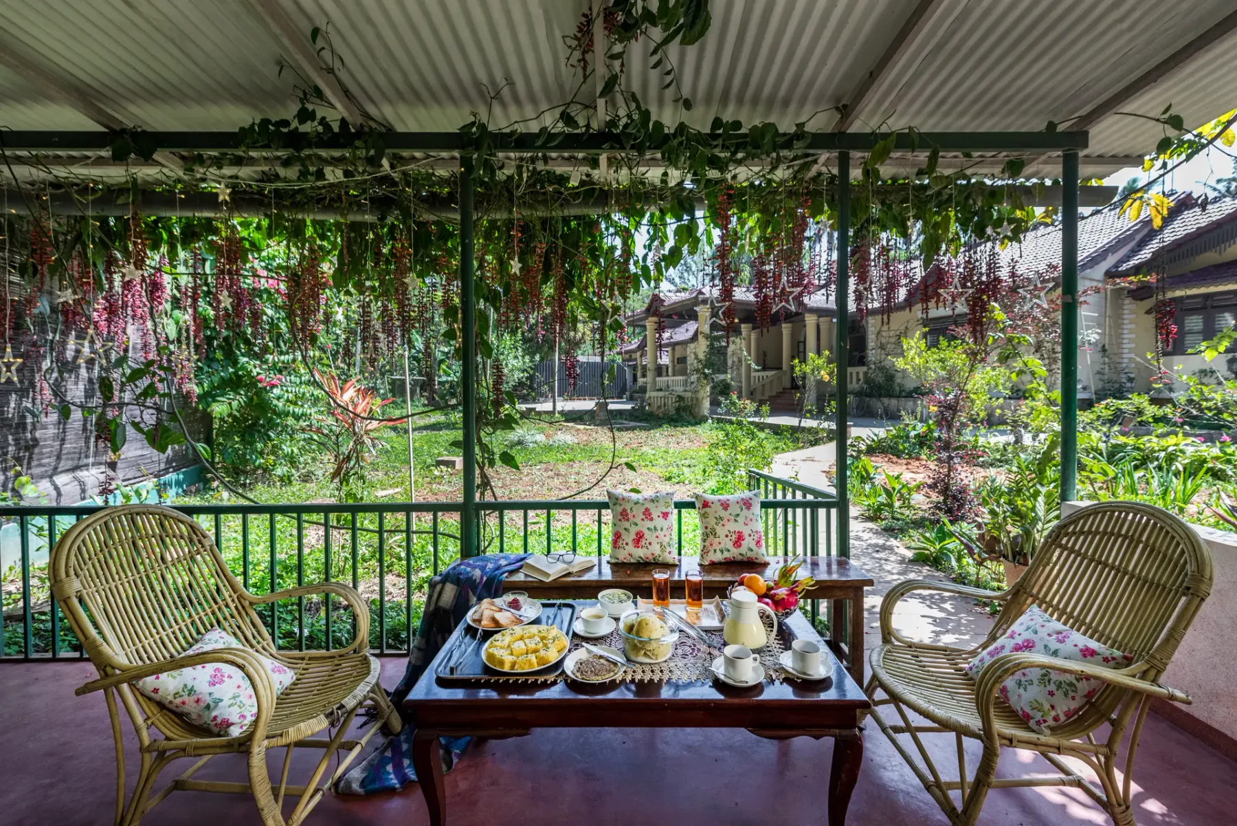 A covered outdoor seating area overlooks a garden, with a table set for tea.