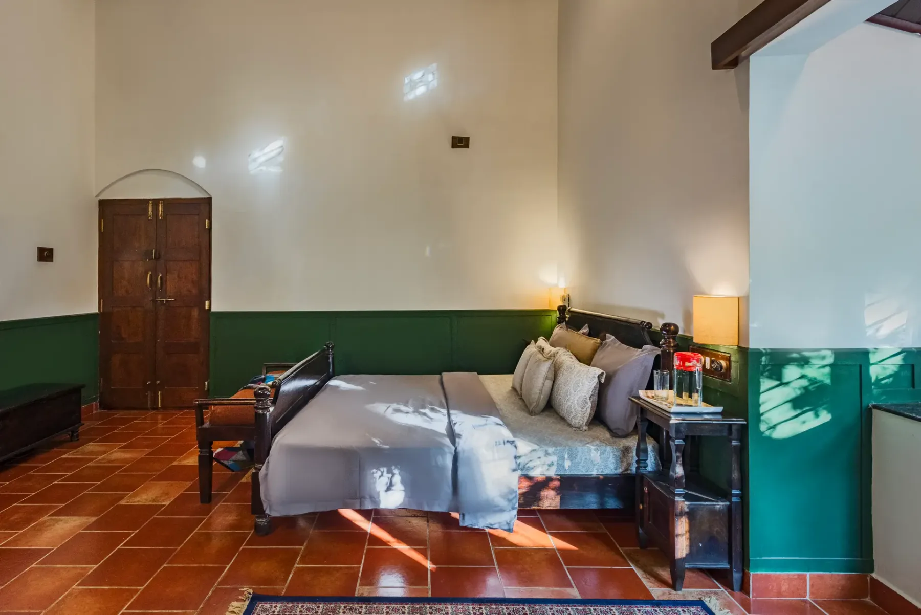 A bedroom with a large bed, bedside table, and green lower walls.