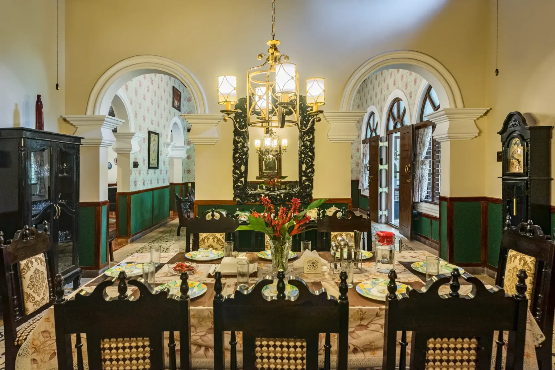 A formal dining room with a long table set beneath a chandelier.
