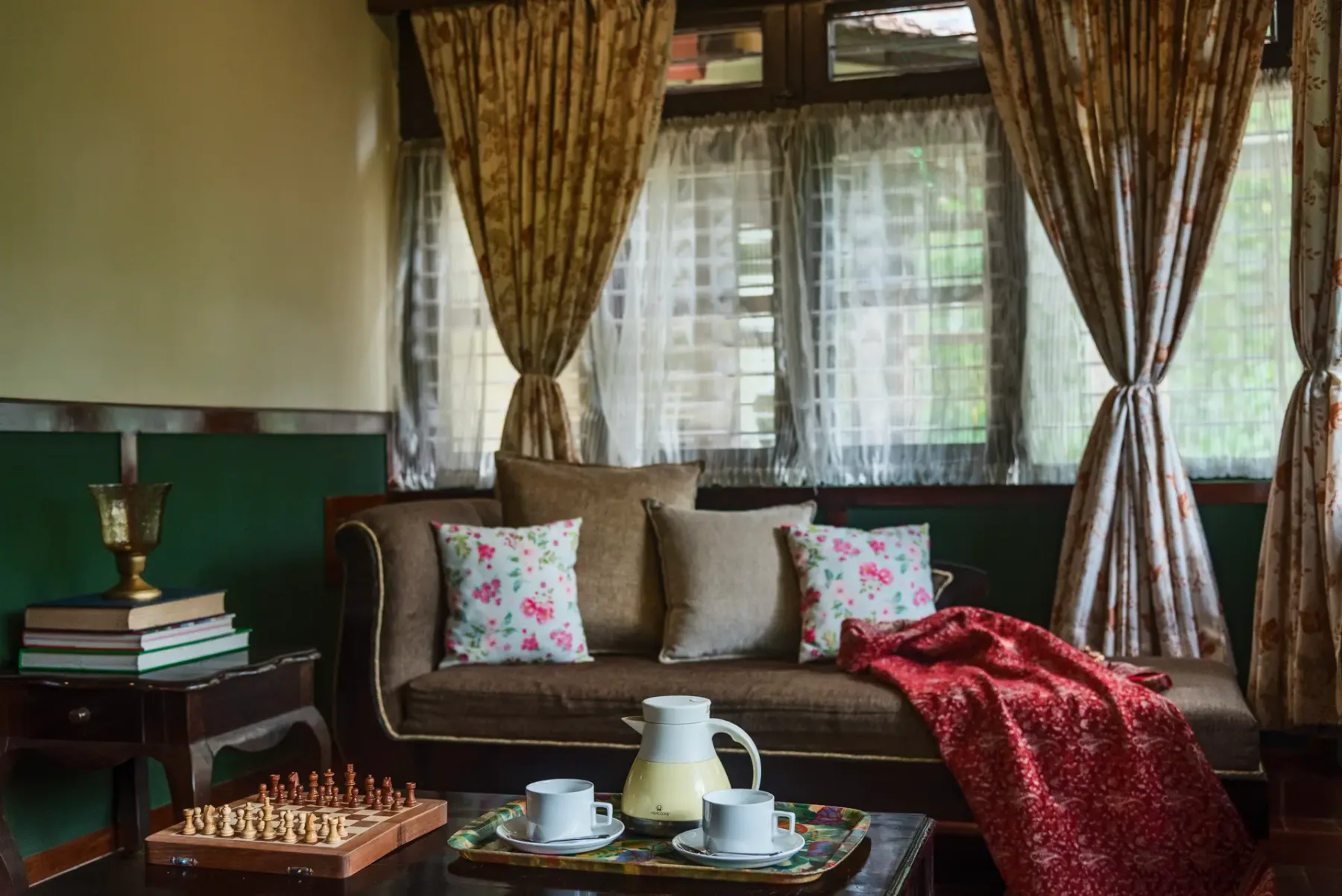 A sitting room with a sofa beneath curtained windows and a tea tray on the table.