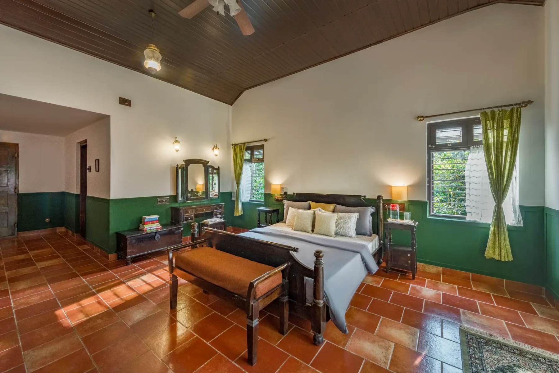 A bedroom with a bed, wooden bench, and windows overlooking the room.