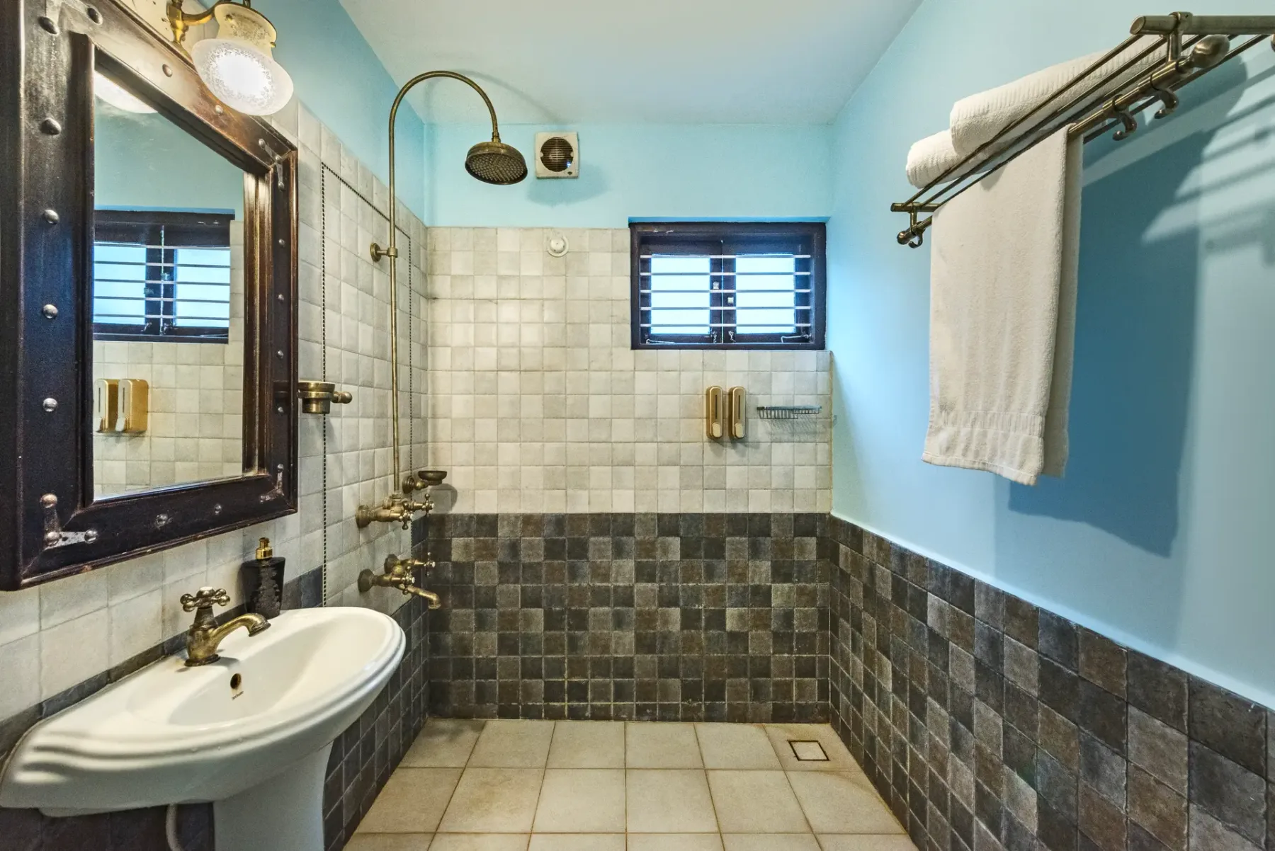 A tiled bathroom with a wall-mounted shower and sink.
