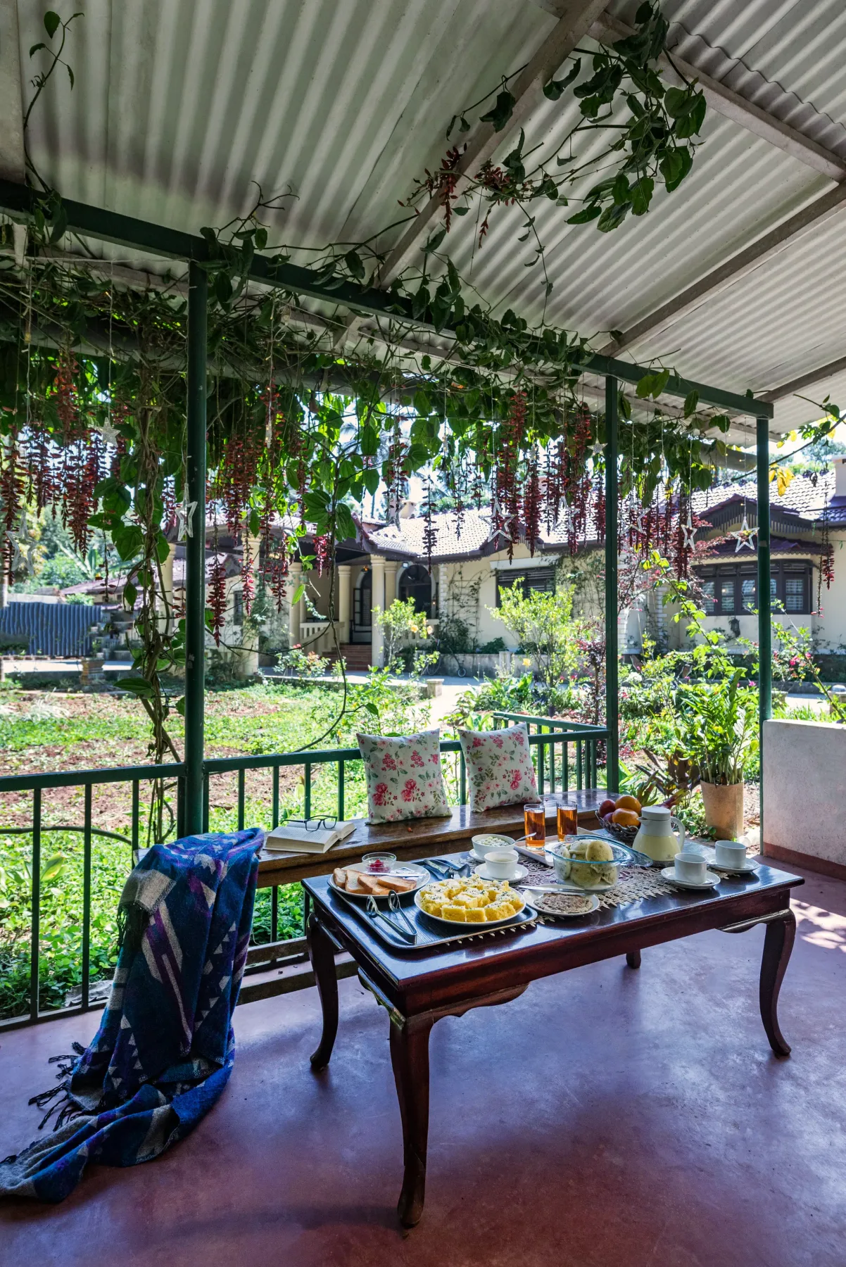 A covered outdoor seating area with a low table and hanging plants.