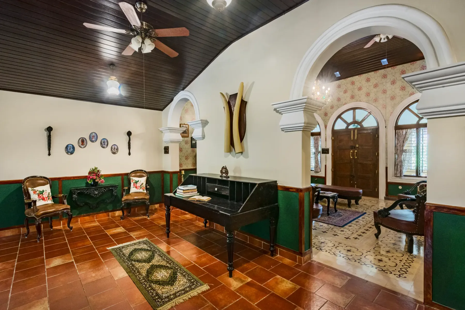 A traditional interior room with a black piano and an arched doorway.