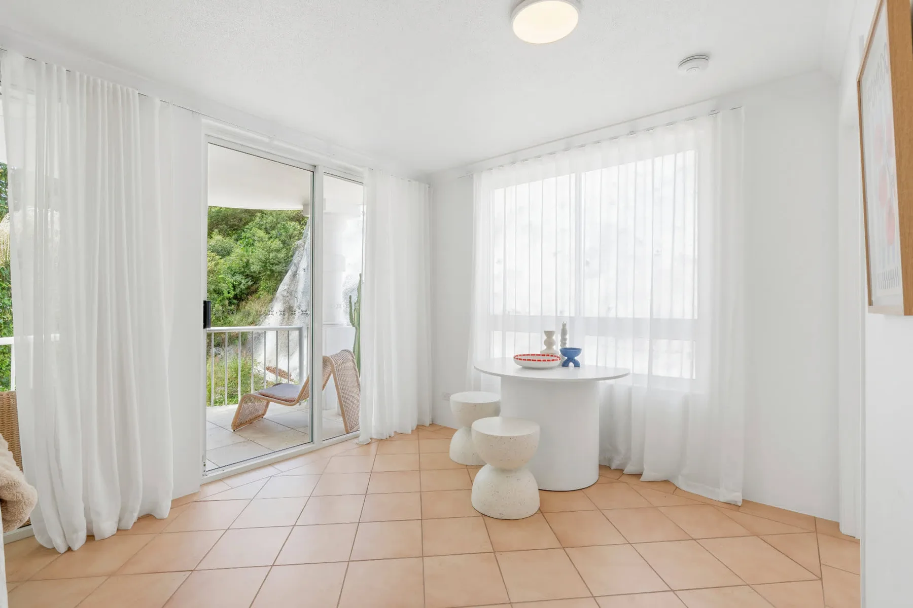 Un luminoso solárium con una mesa redonda junto a ventanas altas con cortinas.