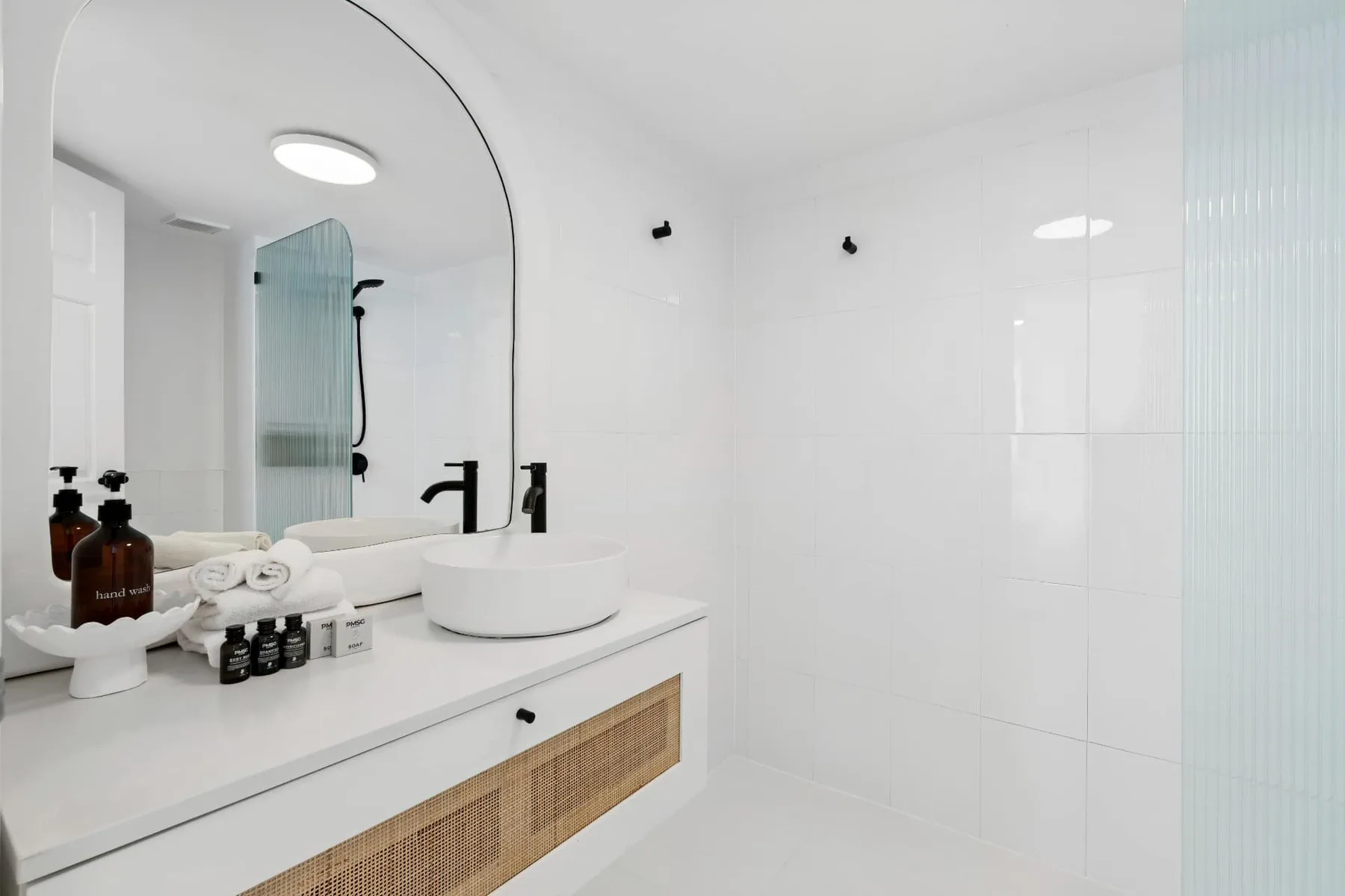 Un baño luminoso con un espejo amplio y un lavabo sobre encimera blanco.