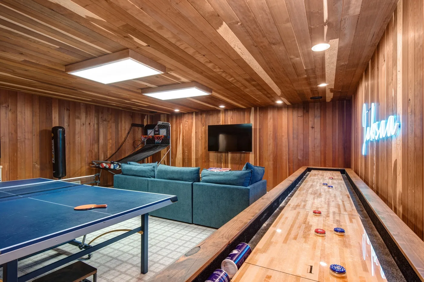 Sala de juegos revestida de madera con mesa de billar, asientos y una mesa de tejo.