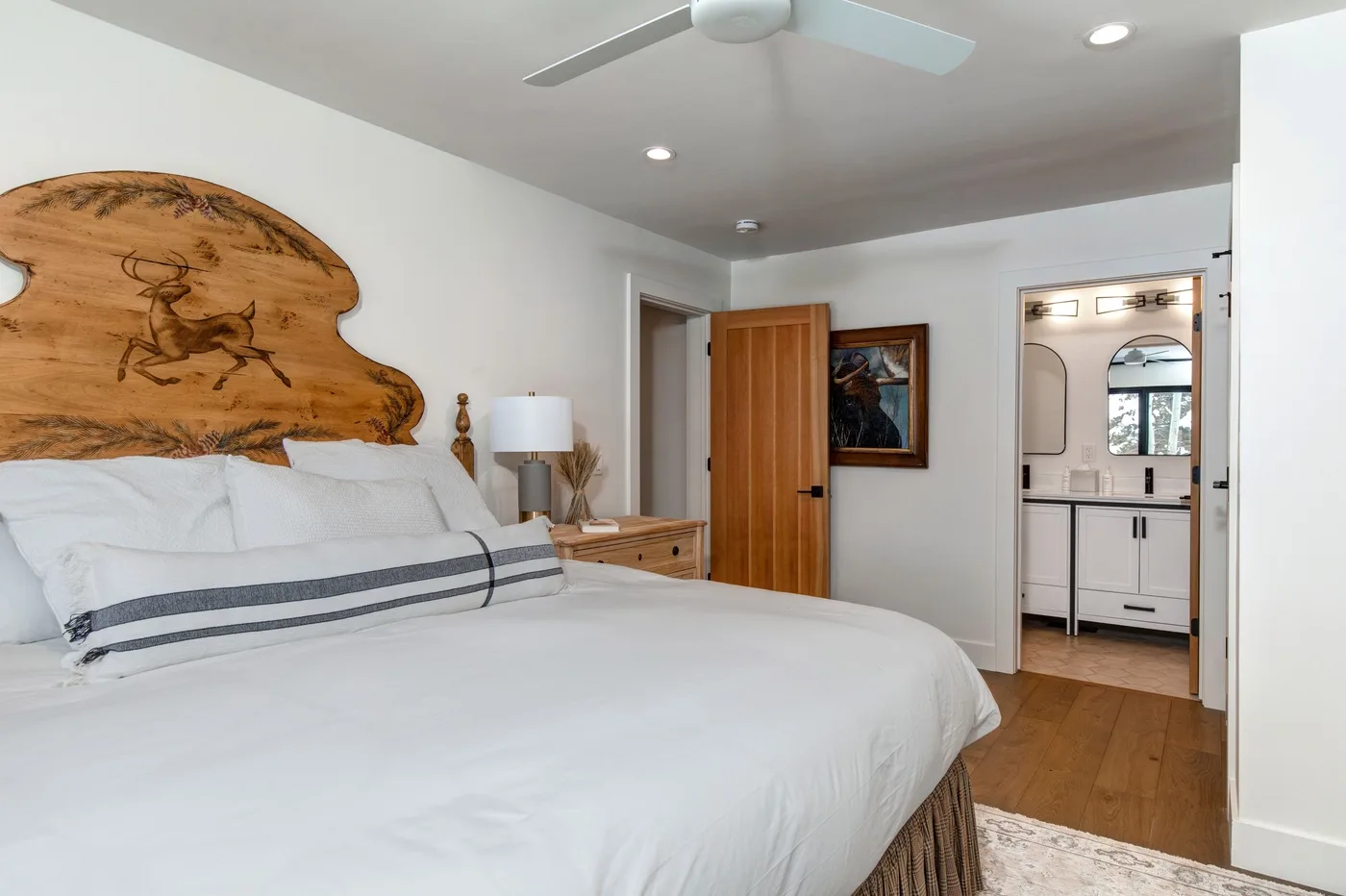 Un dormitorio con una cama grande, un cabecero de madera y una puerta abierta al baño.