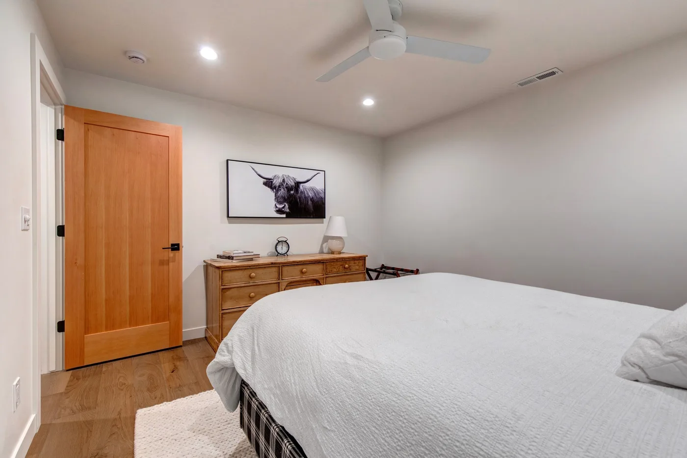 Un dormitorio con una cama, una cómoda de madera y un cuadro de un toro en la pared.