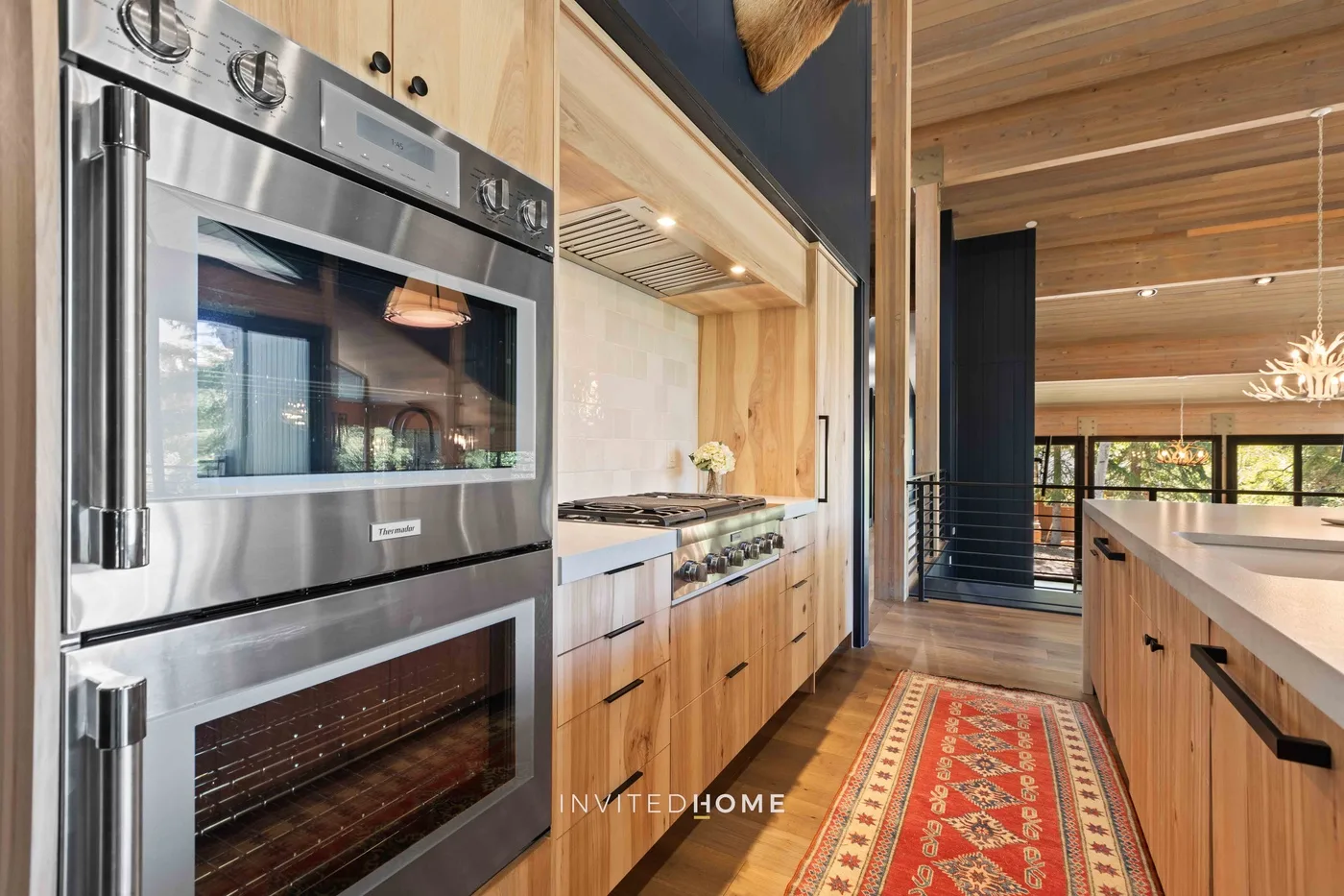 Una cocina revestida de madera con hornos de acero inoxidable y una isla larga.