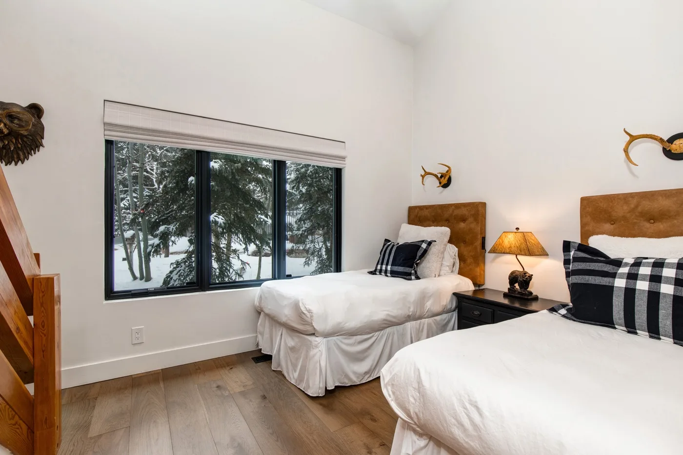 Un dormitorio con dos camas y una ventana con vista a árboles nevados.