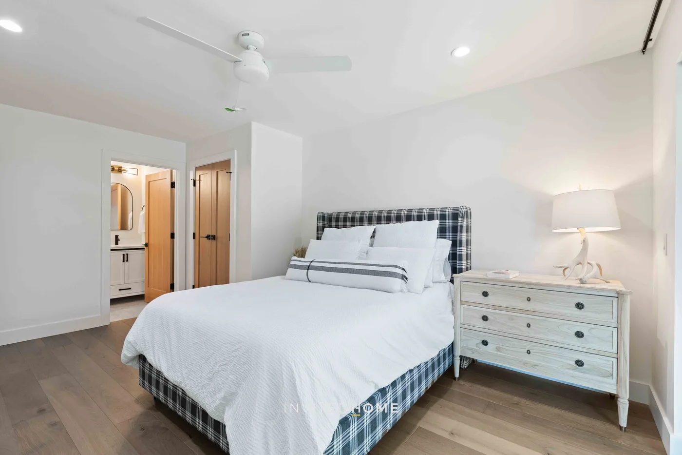 Un dormitorio con una cama bien tendida y una cómoda al lado.
