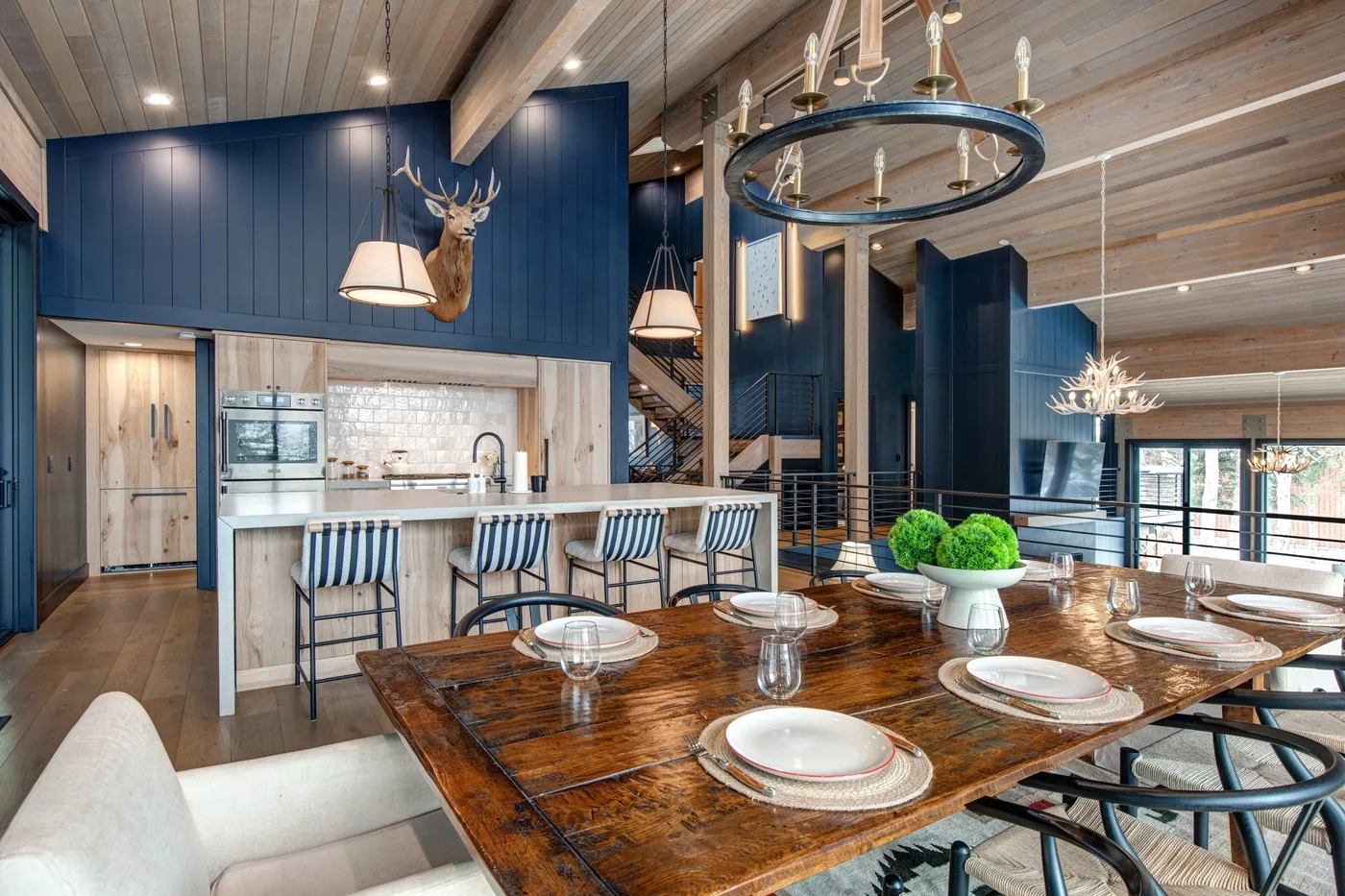 Un comedor con una larga mesa de madera está junto a una cocina con gabinetes azules.