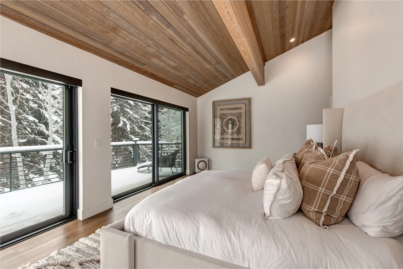 Dormitorio con una cama grande y puertas corredizas de vidrio con vistas nevadas.