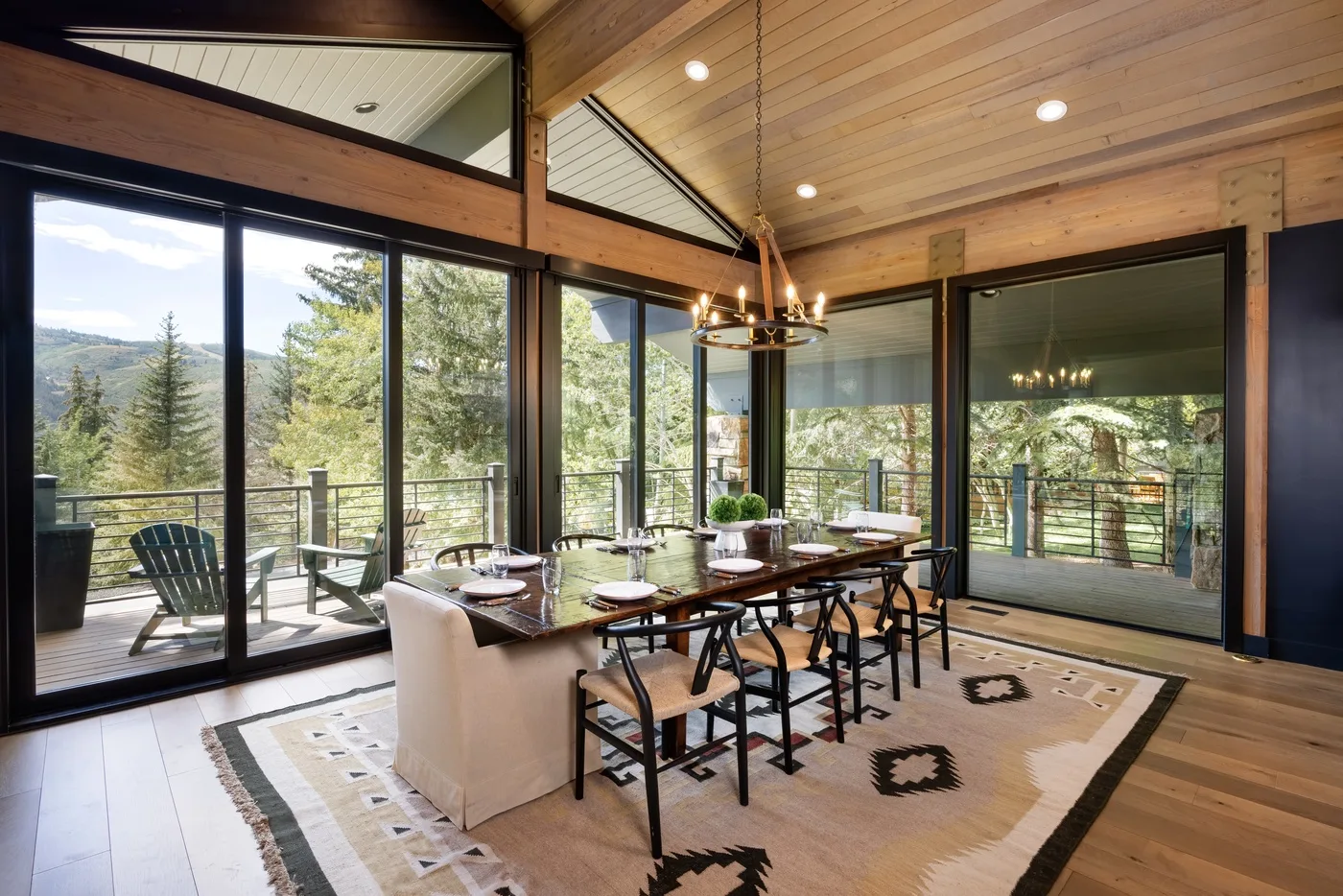Comedor con una mesa larga y grandes ventanas con vistas a los árboles.