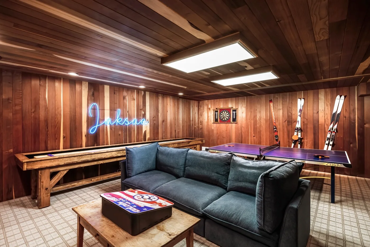 Sala de juegos con paneles de madera, un sofá y una mesa de billar.