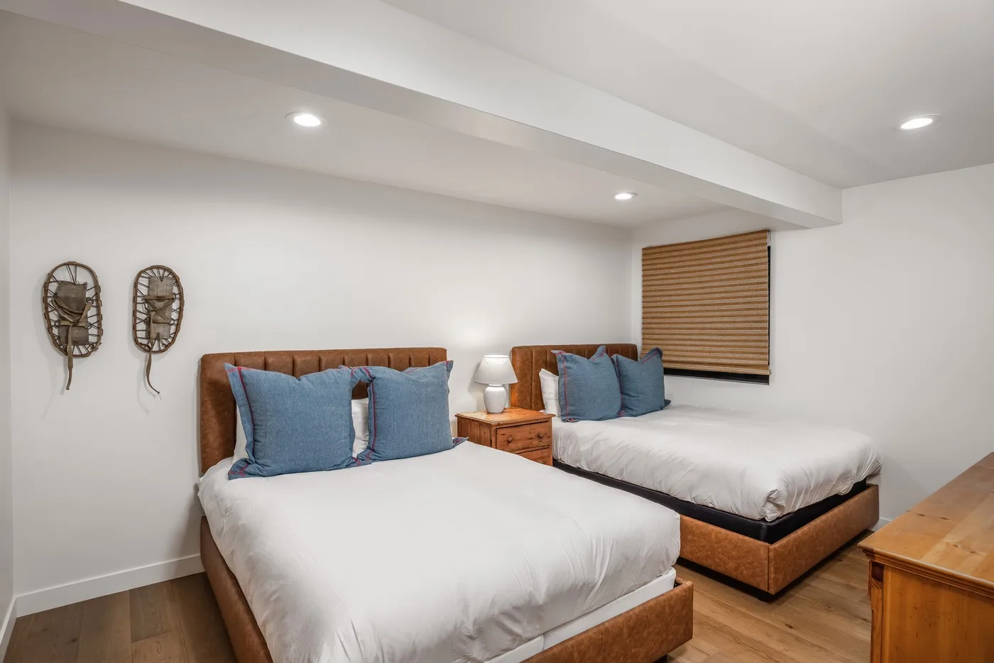 Un dormitorio con dos camas, almohadas azules y una cómoda de madera.