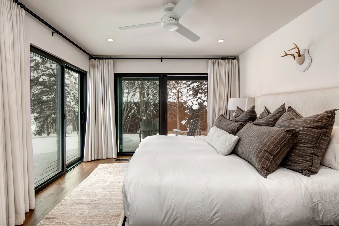Un dormitorio luminoso con una cama grande y puertas de vidrio con vistas a los árboles.
