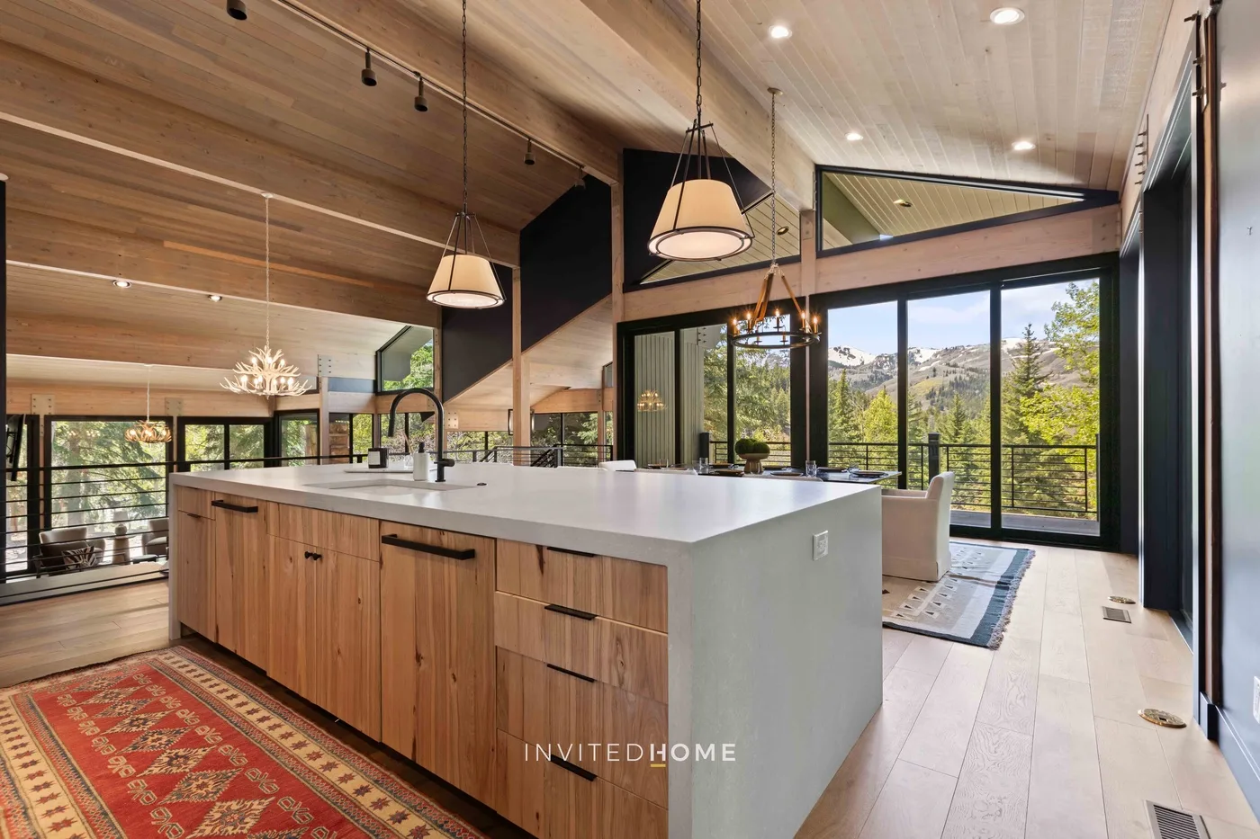 Una cocina abierta y luminosa con una gran isla y ventanas con vistas a los árboles.
