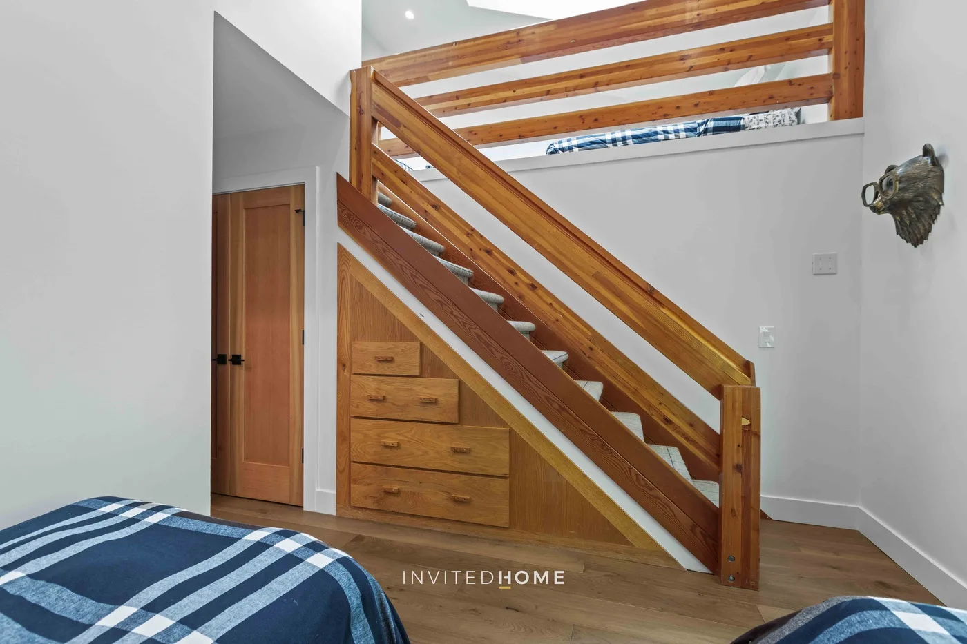 Un dormitorio con una escalera de madera y una cama en primer plano.