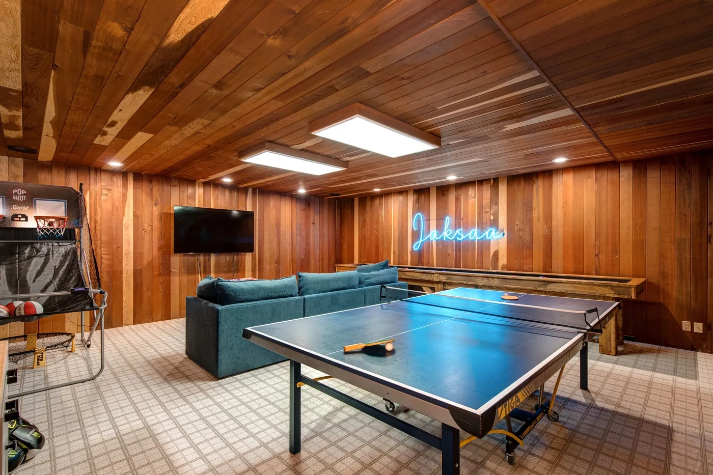 Una sala de juegos revestida de madera con una mesa de ping-pong y asientos.