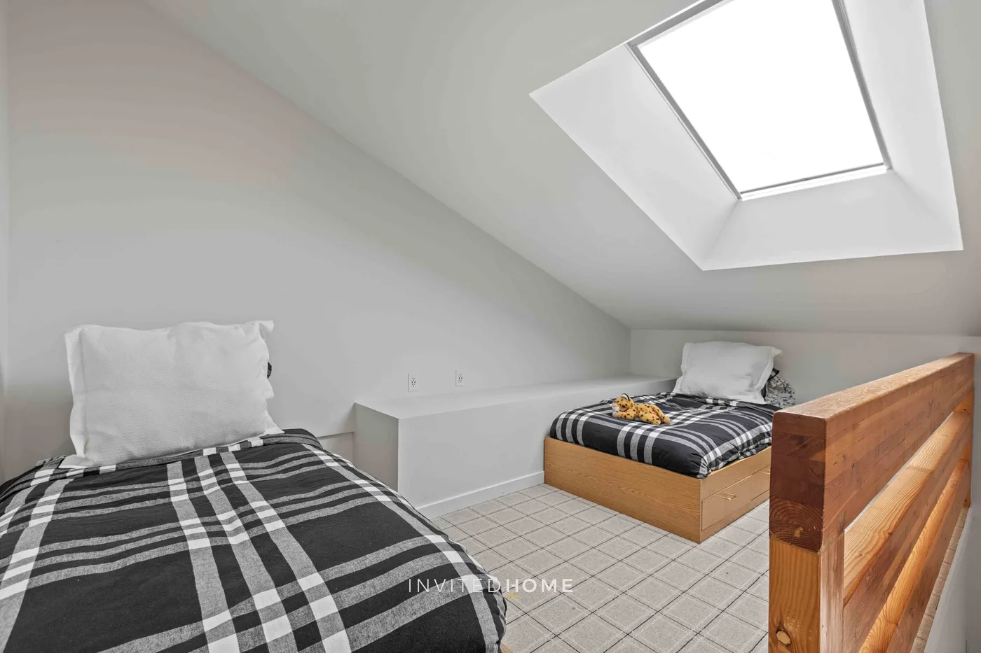 Un dormitorio luminoso con dos camas y un gran tragaluz.