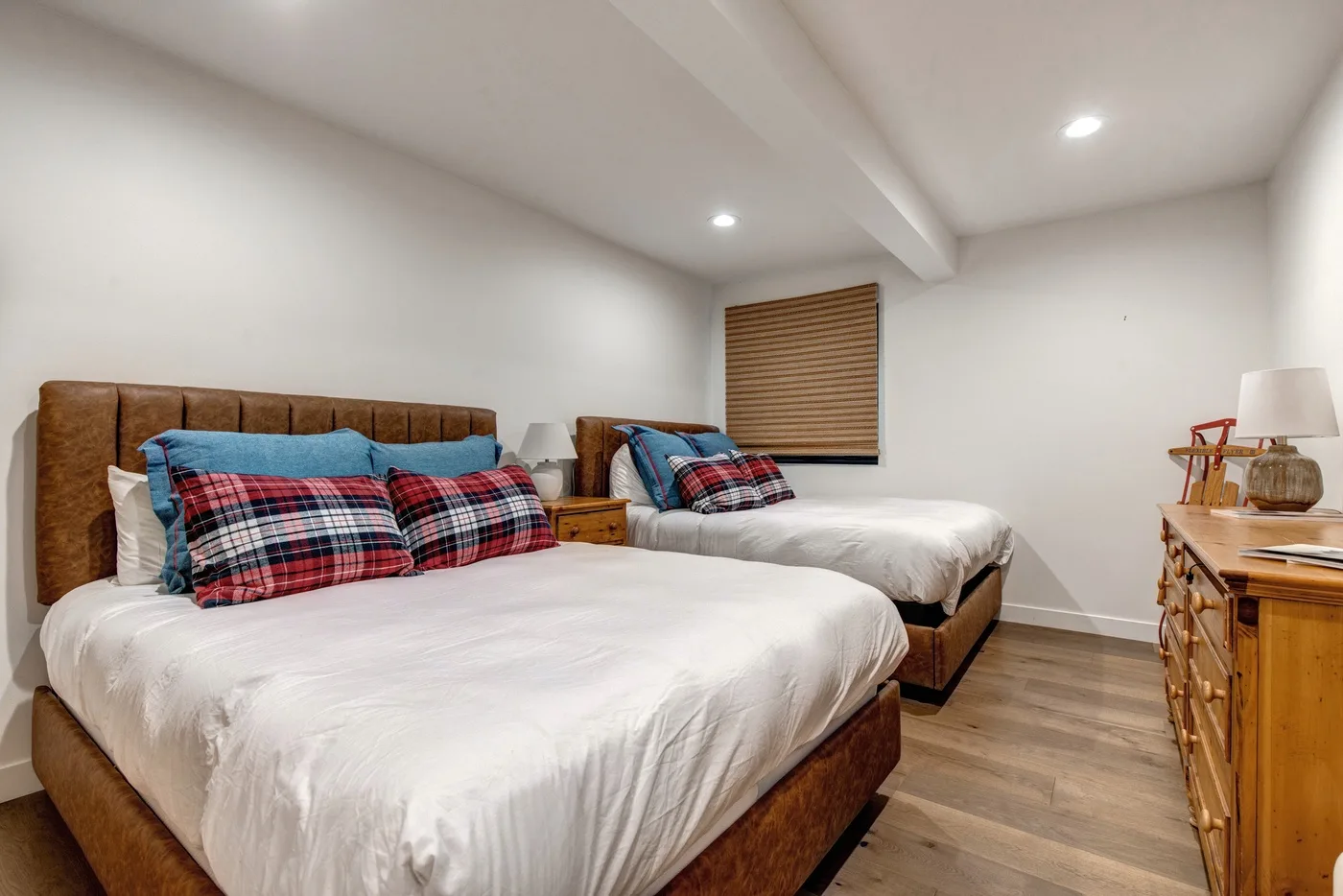 Dormitorio con dos camas, almohadas a cuadros y una cómoda de madera.