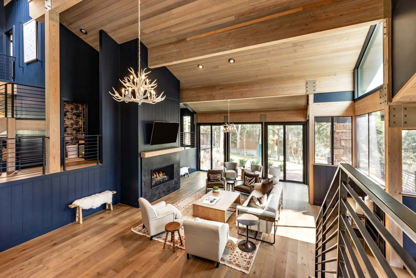 Una amplia sala de estar con techos de madera, grandes ventanas y asientos junto a una chimenea.