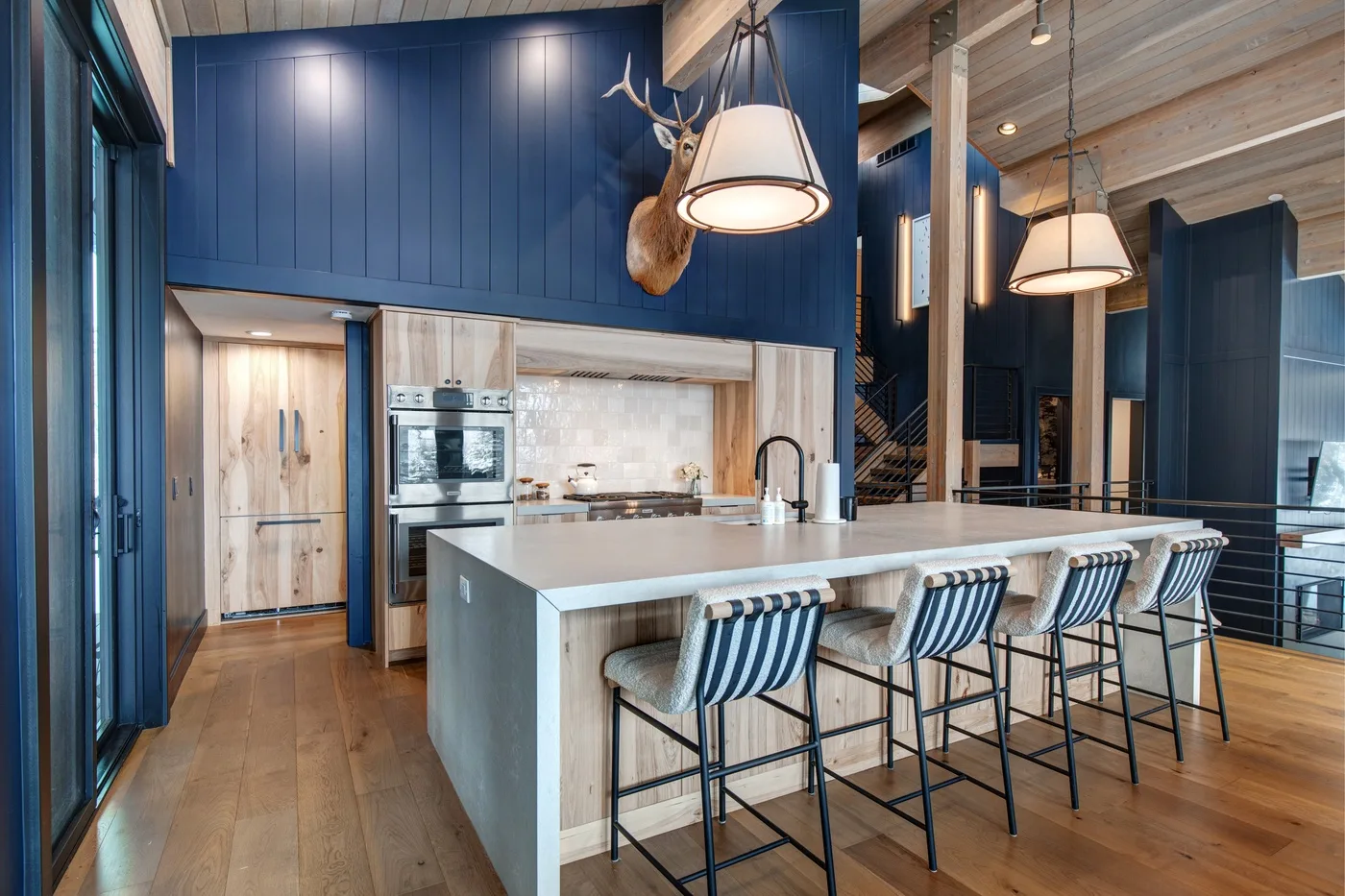 Una cocina amplia con una isla grande, asientos a rayas y paredes con paneles azules.
