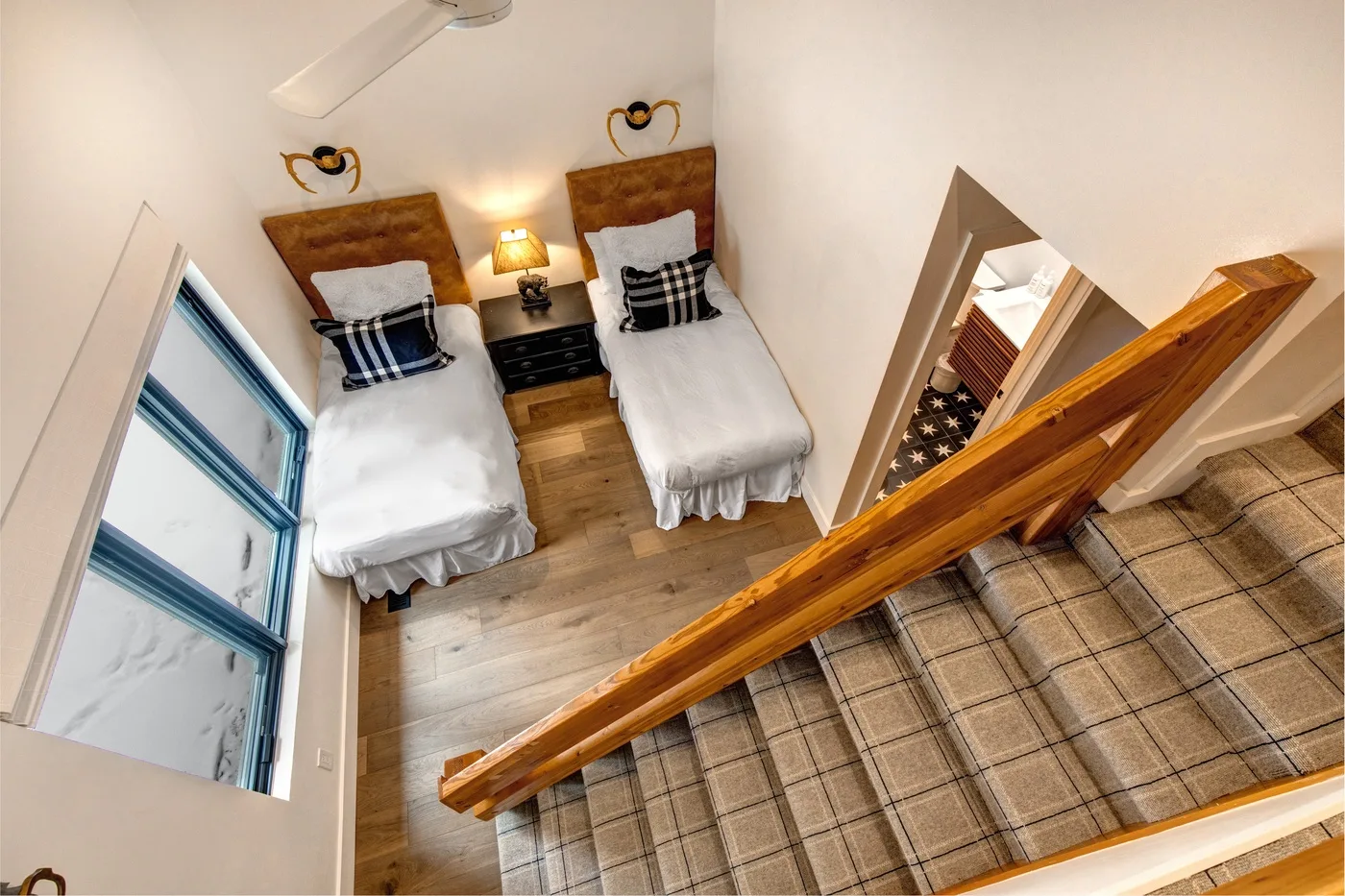 Un dormitorio con dos camas individuales y una escalera de madera.