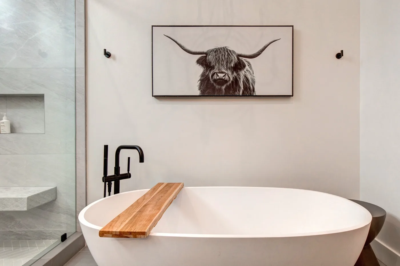 Un baño presenta una bañera independiente bajo una ilustración enmarcada de un animal.