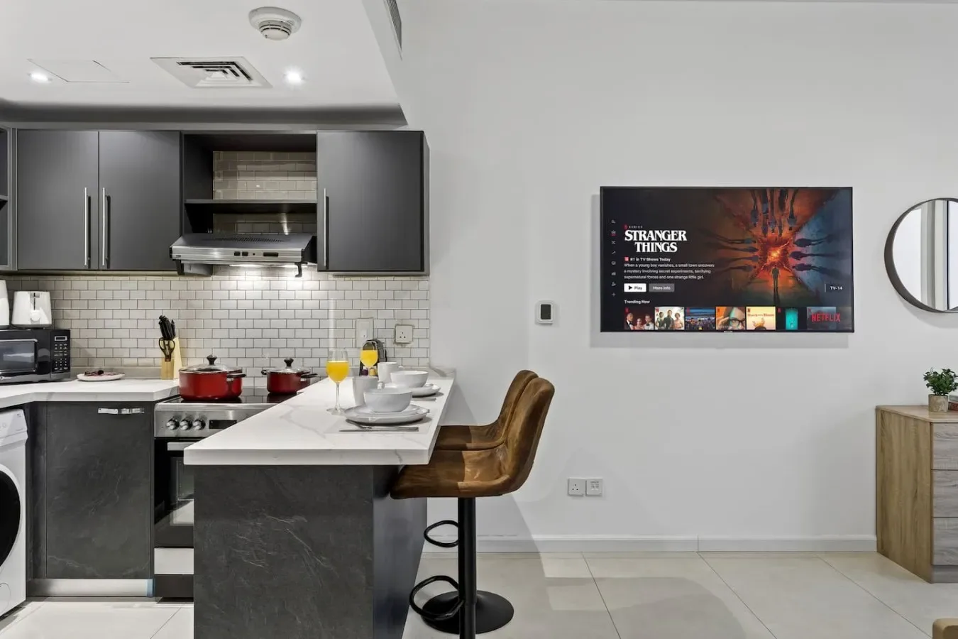 Una cocina moderna y una barra de comedor con un televisor montado en la pared.