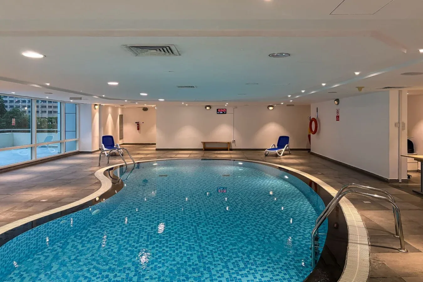 Una piscina cubierta de agua azul, con bordes curvos revestidos de azulejos y asientos.