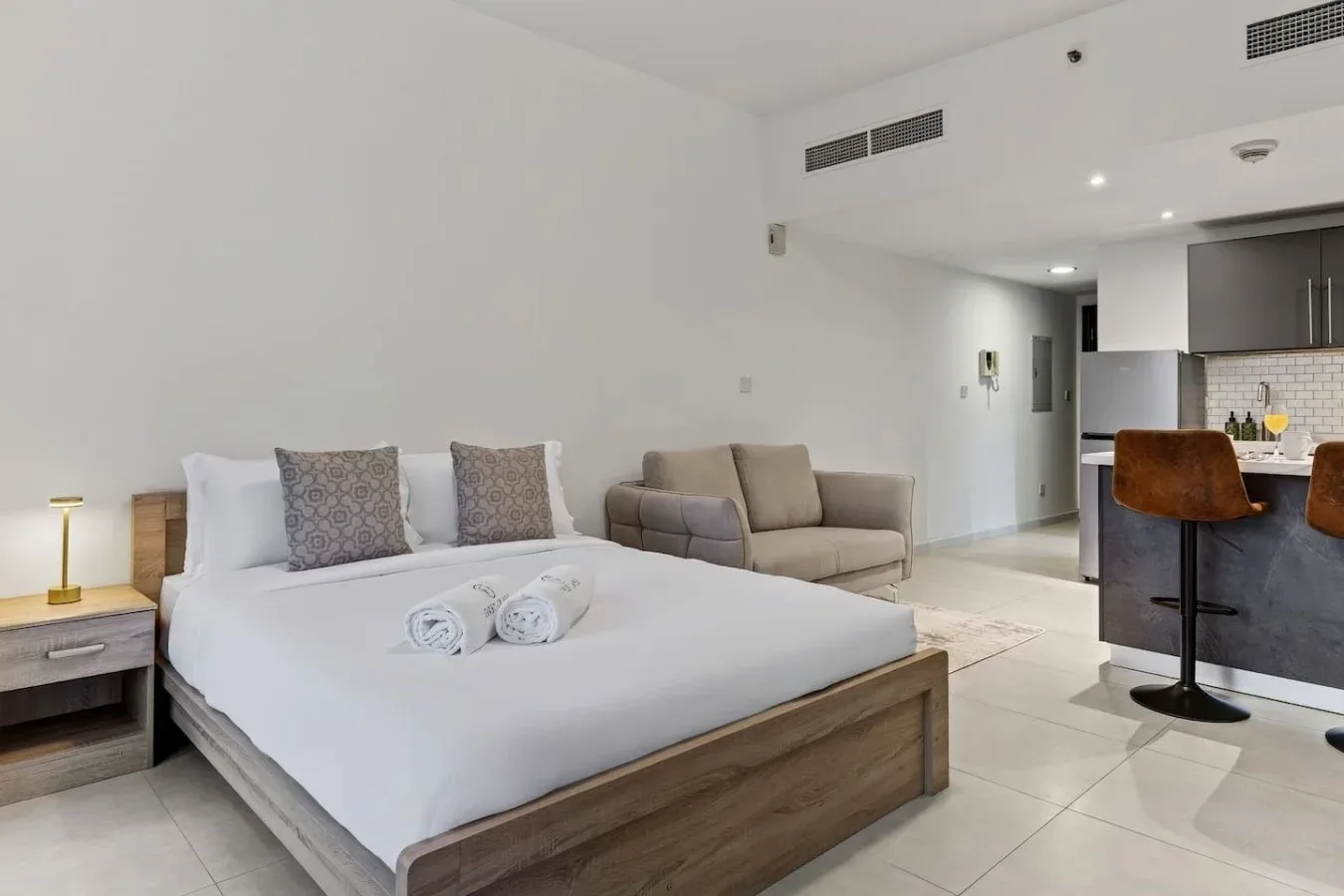 Un dormitorio con una cama grande y una pequeña zona de estar junto a la cocina.