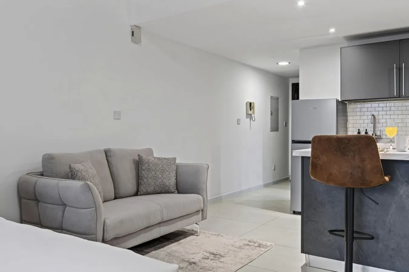 Una sala de estar con asientos grises junto a una cocina abierta.