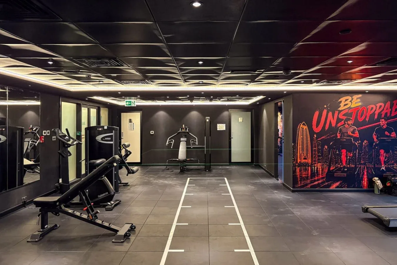Una zona de gimnasio con máquinas de ejercicio y un carril marcado en el suelo.