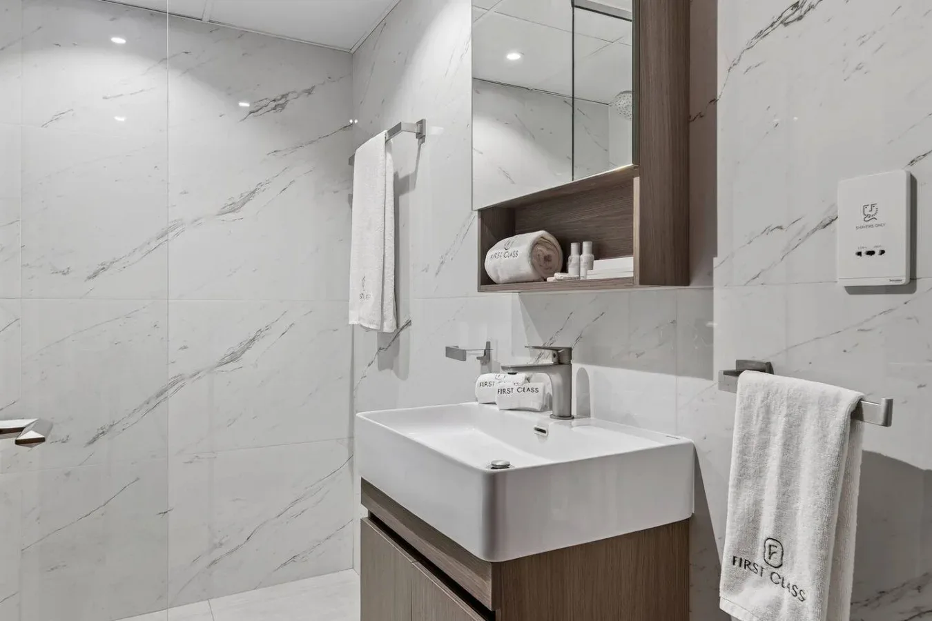 Un baño moderno con lavabo blanco, espejo y paredes revestidas de azulejos.