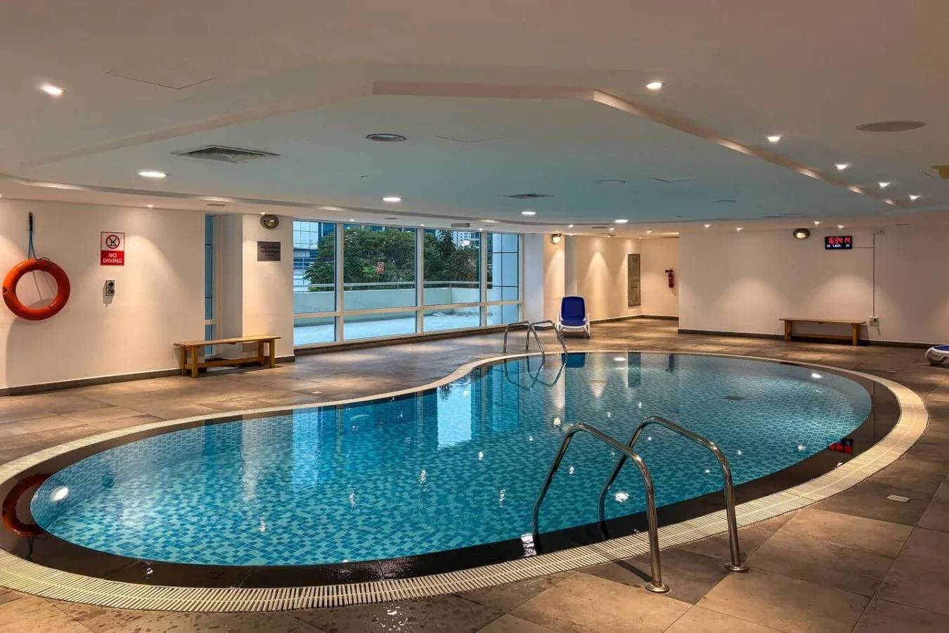 Una piscina cubierta con grandes ventanas y asientos junto al borde.