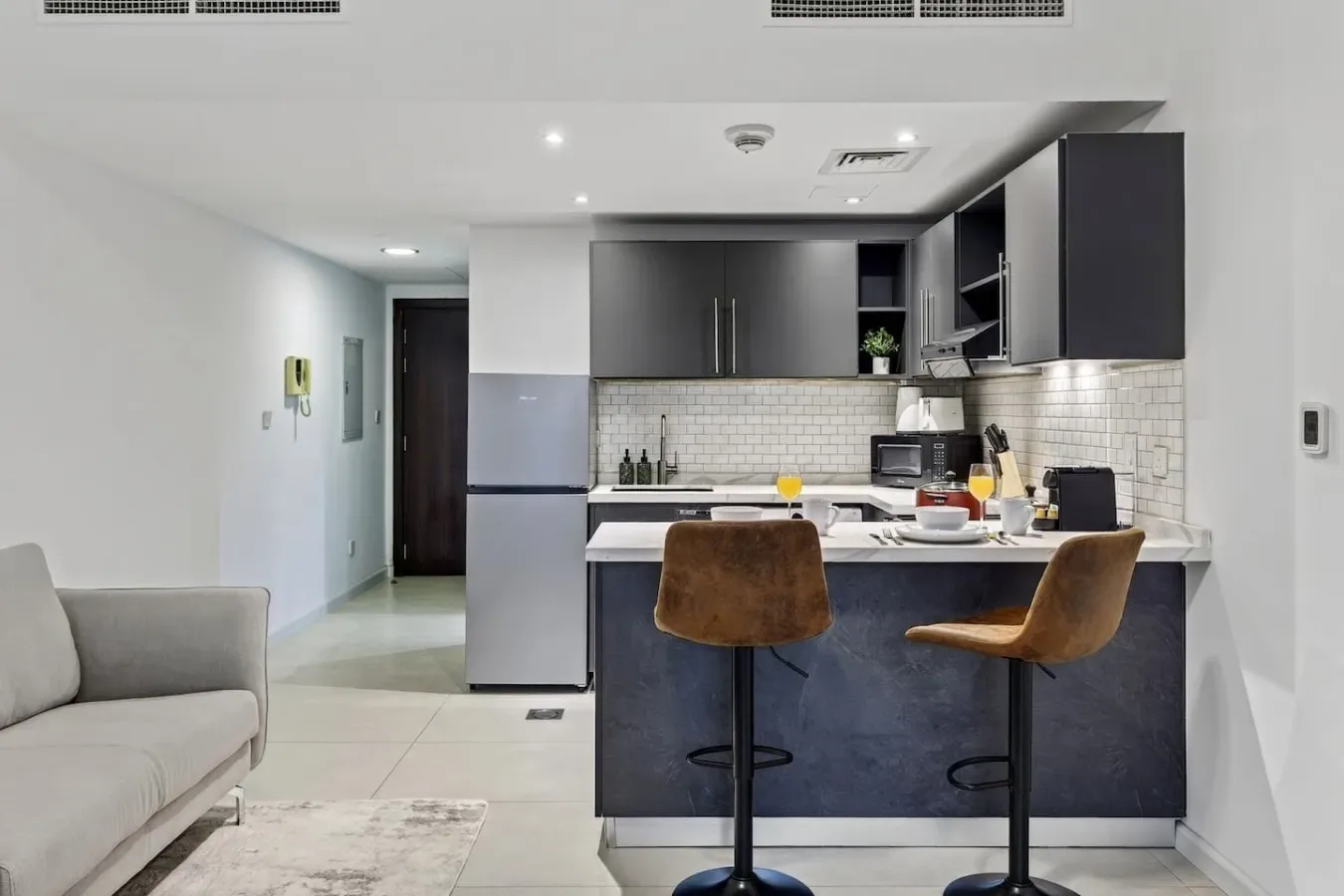 Una cocina abierta al salón, con una isla oscura y asientos claros.