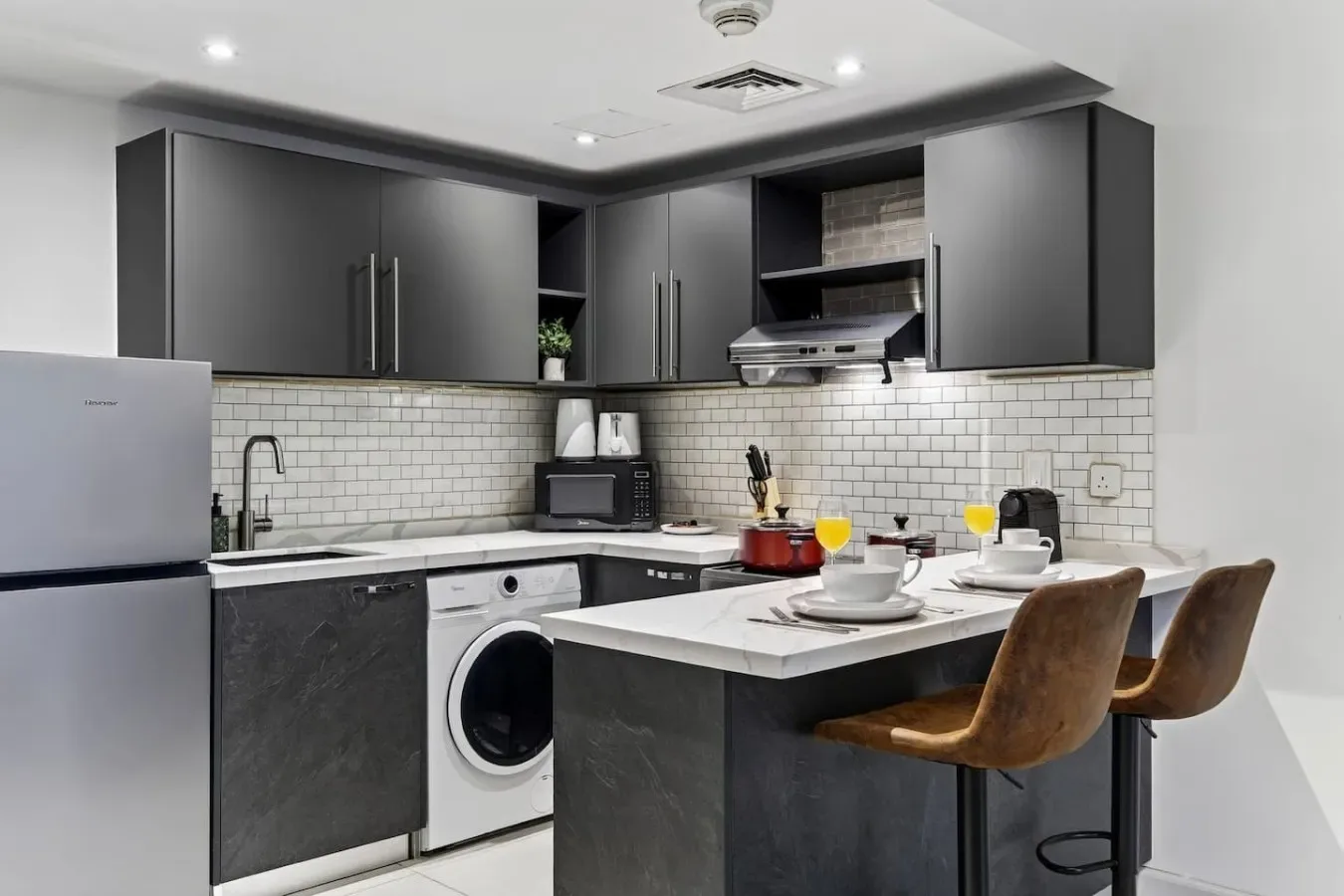 Una cocina moderna con gabinetes oscuros, una encimera central y asientos.