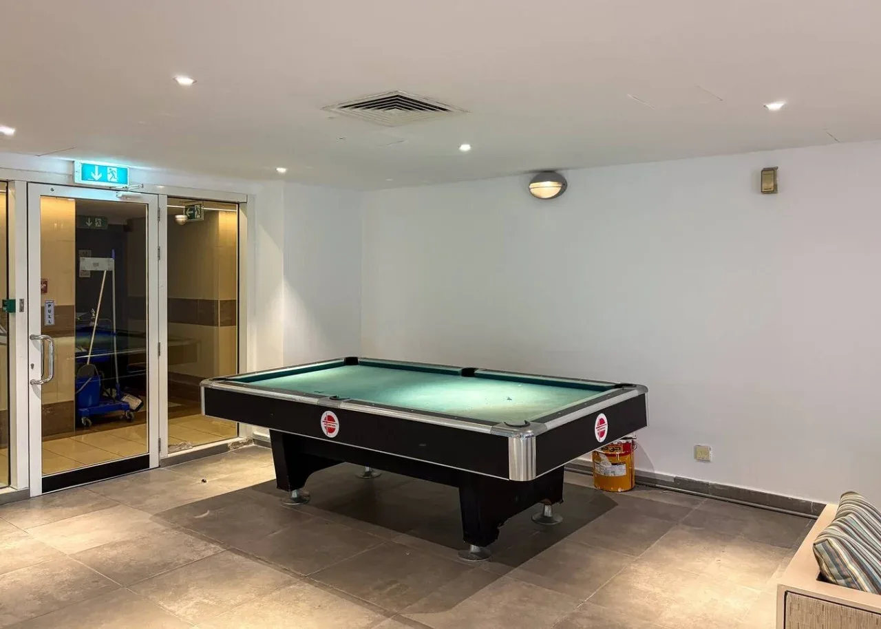 Una sala de billar con una mesa de pool y puertas de vidrio.