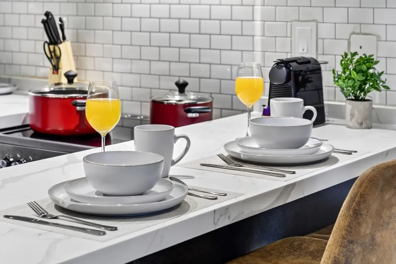 Una encimera de cocina está puesta con vajilla, junto a ollas y una cafetera.