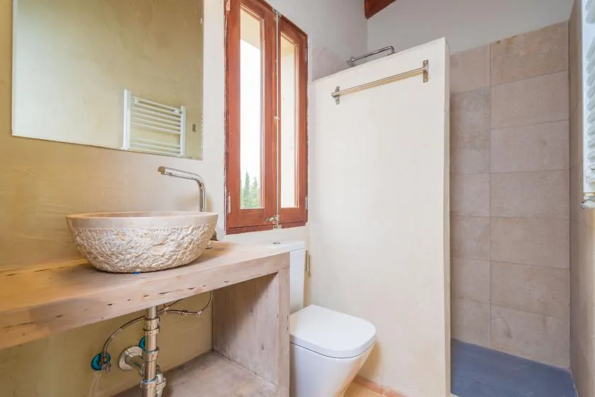 Un baño con un lavabo sobre encimera, un inodoro y una zona de ducha con azulejos.