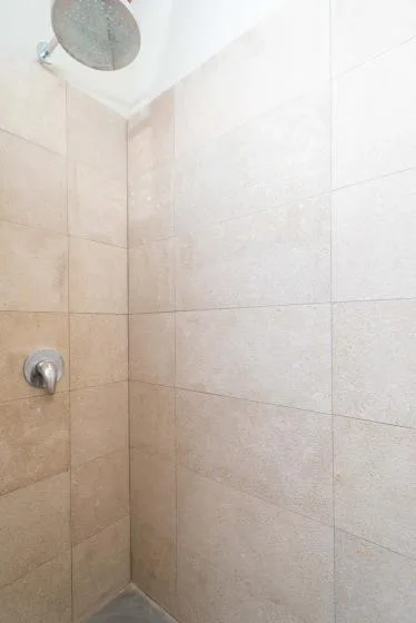 Una ducha revestida de azulejos con un cabezal montado en la pared.