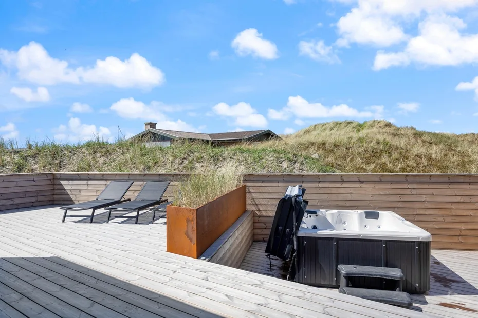 Una terraza en la azotea con jacuzzi, asientos y hierba de dunas alrededor.