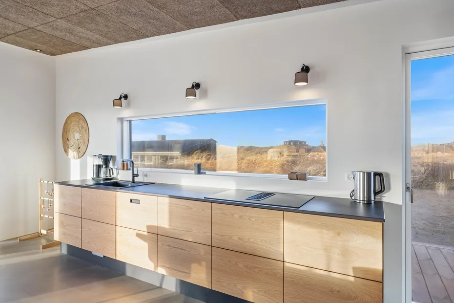 Una cocina moderna con gabinetes de madera clara y una amplia ventana con vistas al paisaje.
