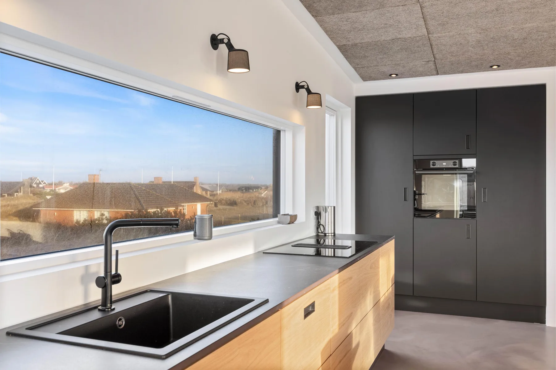 Una cocina moderna con una encimera larga, fregadero y una ventana amplia.