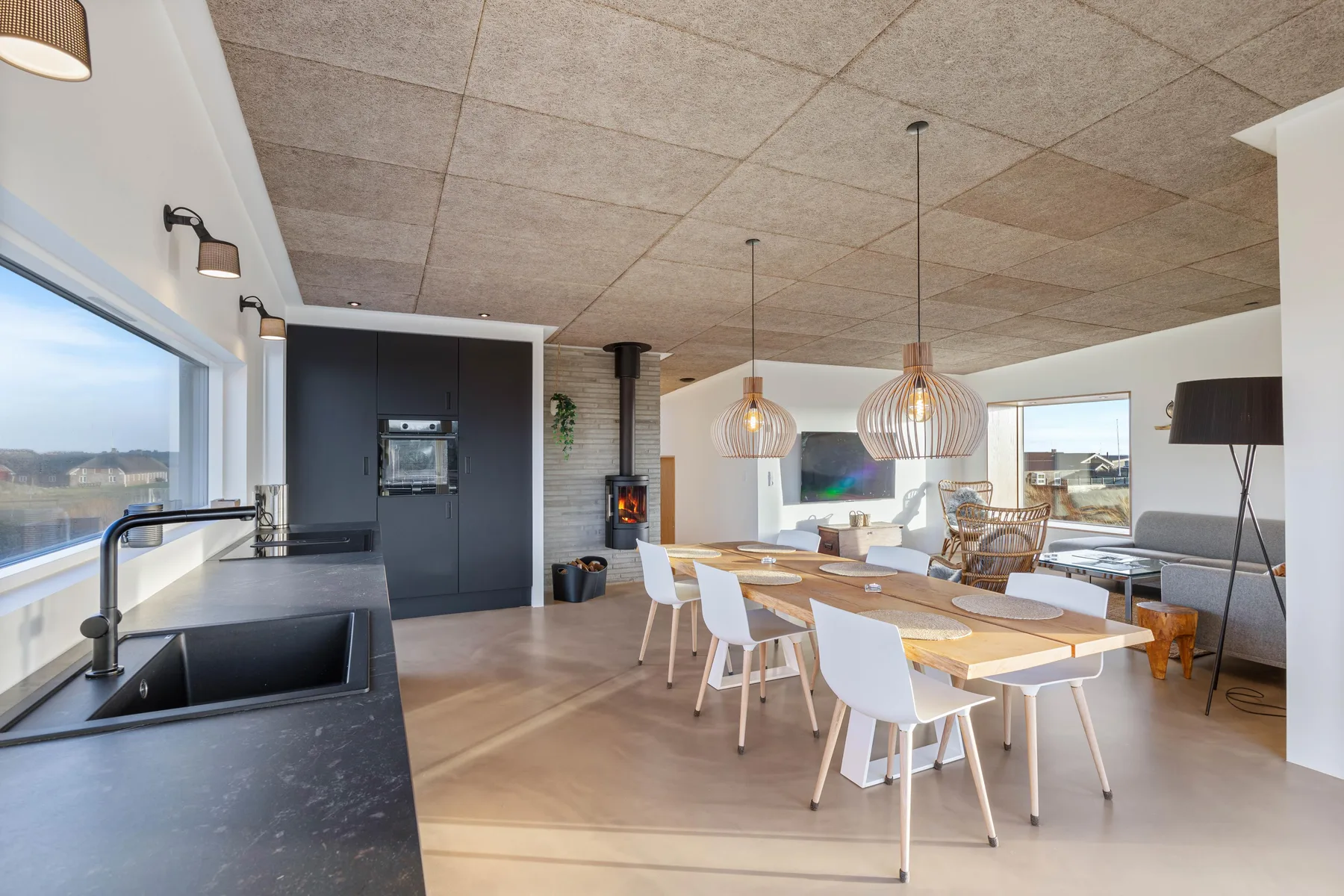 Una cocina abierta y comedor con una mesa larga y grandes ventanas.
