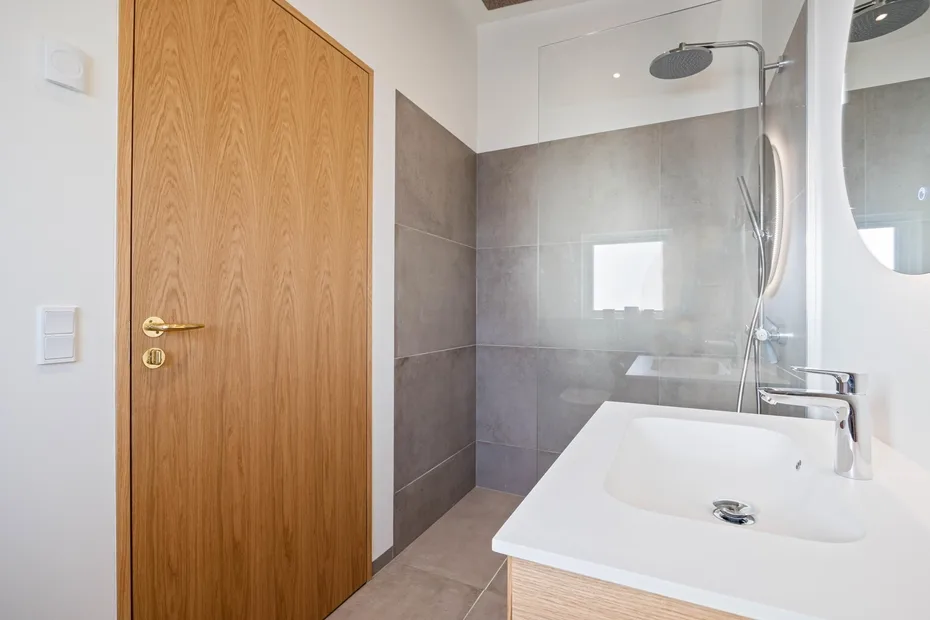 Un baño moderno con ducha a ras de suelo y lavabo blanco.